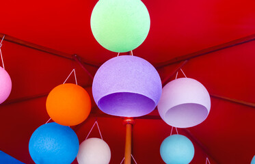 Colorful thread lamp hanging on umbrella structure on background