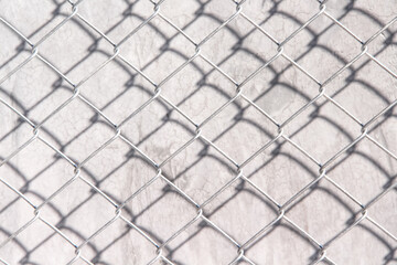 Mesh metal fence texture with black shadow on concrete grey wall background