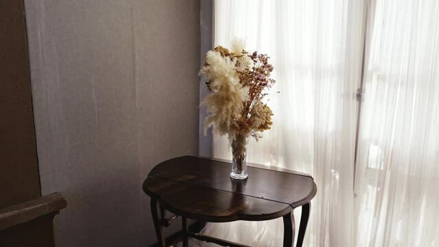 vase with assorted flowers on a table in a room filled with white light