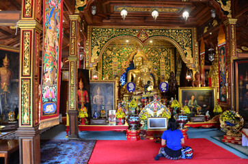 Thai travelers women people travel visit respect praying blessing wish myth mystical worship ancient buddha statue of Wat Ming Muang or Ming Mueang temple on February 24, 2015 in Chiang Rai, Thailand