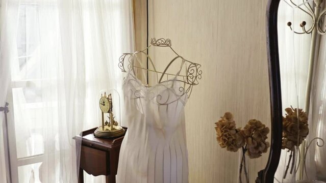lingerie dress displayed on a rack in a room with antique decoration and lots of natural light
