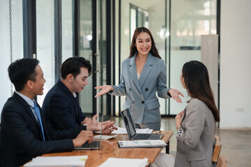 Smiling businesswoman discussing report with team. Office meeting with active participation and teamwork. Corporate business and teamwork concept.