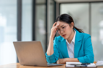 Stressed asian businesswoman working at laptop in office. Work pressure and deadline concept.