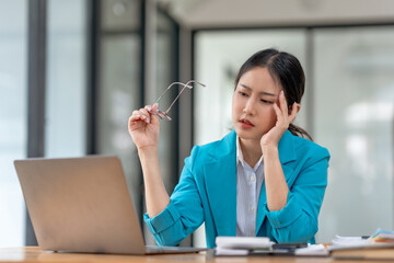 Stressed asian businesswoman working at laptop in office. Work pressure and deadline concept.