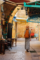 Beautiful girl traveler in a hat and with a backpack exploring the historical city.