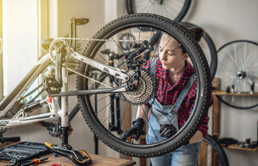 Woman fixing a mountain bike in a workshop. Concept of preparation for the new season, repair and maintenance - 772737099