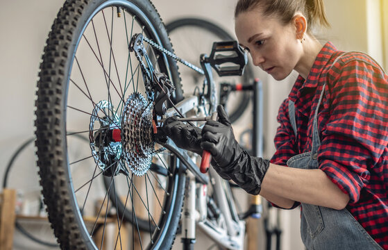 Woman fixing a mountain bike in a workshop. Concept of preparation for the new season, repair and maintenance