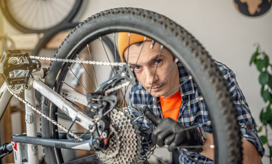A male bicycle mechanic repairs a mountain bike in a workshop. The concept of preparation for the new season, repair and maintenance