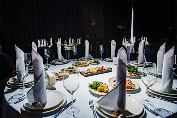The table is elegantly set with tableware including plates, glasses, napkins, and candles, creating...