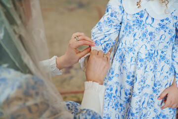 Mom fastens the cuff on the sleeve of her daughter's dress. Mother's love and care.