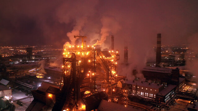 Night top view of the blast furnace of a metallurgical plant. Bright lights, smoke and smog of an industrial area