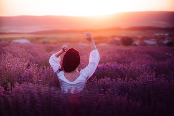 Woman lavender field sunset. Back view woman in a white blouse. Aromatherapy concept, lavender oil,...