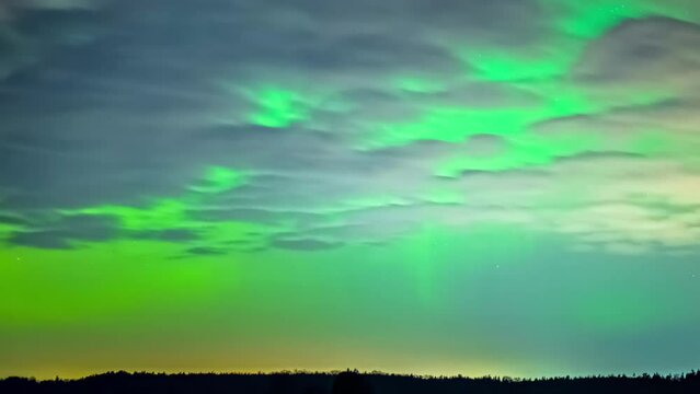 Beautiful shot of the Northern Lights in a clear sky with few clouds and shooting stars in the sky.