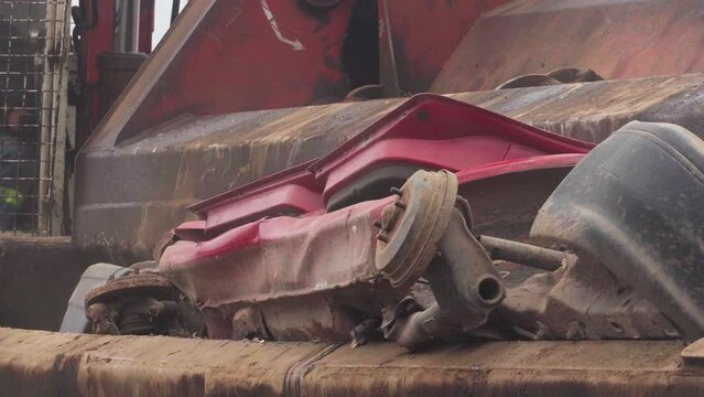 A car being crushed by a car crusher in a junkyard.
