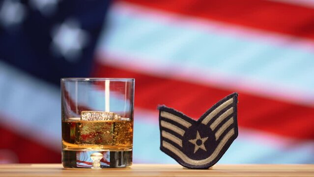 Whiskey Glass and Air Force Military Badge in Front of American Flag Waving