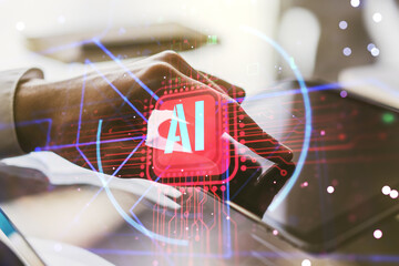 Double exposure of creative artificial Intelligence abbreviation and hand working with a digital tablet on background. Future technology and AI concept - obrazy, fototapety, plakaty