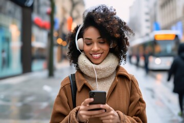 African young woman is listening to music on smartphone with headphones outdoors