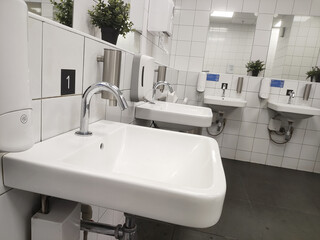 Modern bathroom sink and touchless faucet in public toilet and restroom.