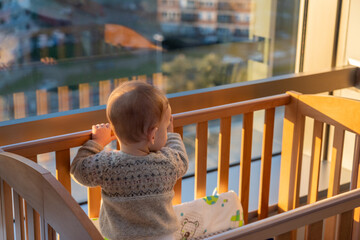 A child looks out of the window of a tall building. Sadness and hope concept