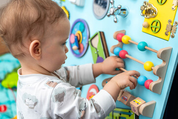 A child enthusiastically plays with toy abacus on a busy board