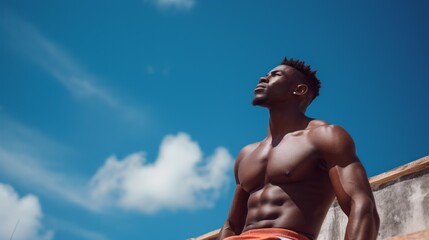 A man with a muscular body is standing on a ledge, looking up at the sky