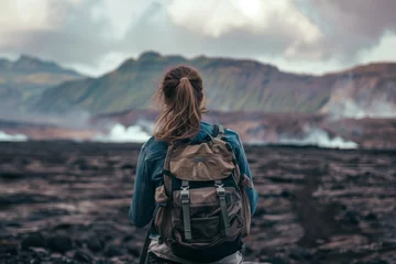 Fotobehang woman with backpack staring at ashcovered landscape © studioworkstock
