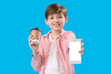 Little boy with cup of cocoa and mobile phone on blue background. Children's Day celebration