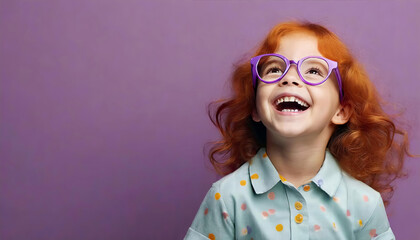 Cute red haired little girl with eyeglasses isolated on solid purple studio background.