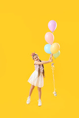 Little girl in crown with balloons on yellow background. Children's Day celebration