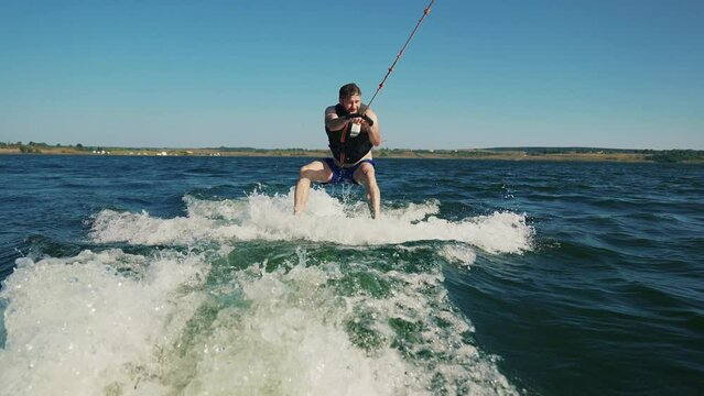 A beginner wakeboarder learns to ride a wakeboard. A man makes a funny start on a wakeboard. Wakeboarding is amateur. Wakesurfing