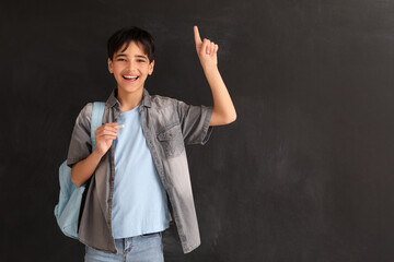 Little boy pointing at something against blackboard. Children's Day celebration