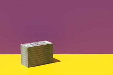 Stack of US 100 dollar bill paper currency on yellow purple background. - obrazy, fototapety, plakaty