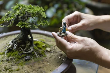Gordijnen hands placing a miniature figurine beside a bonsai © studioworkstock