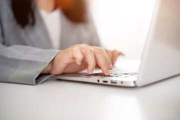 A cropped image of a businesswoman working or browsing on the laptop, working in a modern office.