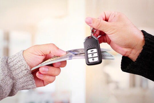 Car trading or loan concept , Banknotes and car keys in hand to exchange