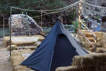 selective focus black octagonal tent on the edge of the rapids River in the forest, camping area on...