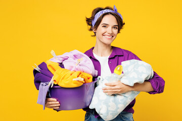 Young smiling happy woman she wear purple shirt do housework tidy up holding look at basin with...