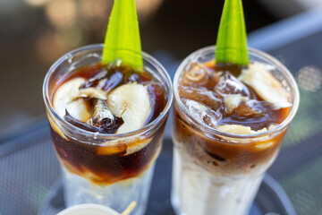 Iced coffee mixed with milk in a clear glass Coffee mixed with coconut water and coconut meat, decorated with pandan leaves on top for added aroma