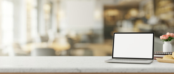 A white-screen laptop computer mockup on a wooden table in a contemporary cosy coffee shop.