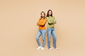 Full body young friends two women they wear orange green shirt casual clothes together hold hands...