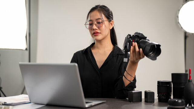 A professional Asian female photographer is focusing on checking images on her laptop.