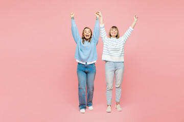 Obraz premium Full body elder parent mom with young adult daughter two women together wears blue casual clothes raise up hands do winner gesture isolated on plain pastel light pink background. Family day concept.