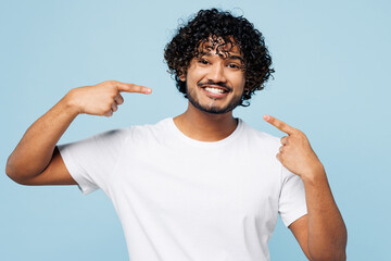 Young smiling cheerful happy Indian man he wear white t-shirt casual clothes point index finger on...