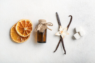 Composition with vanilla extract, sticks and dried orange slices on light background