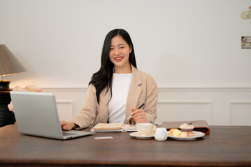 An attractive Asian businesswoman is sitting at her desk in her beautiful aesthetic office.