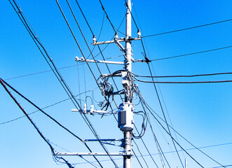 View below of Transformers small sphere size and electric wire phone lines. Energy and technology. Electrical post on electric power. electrical device. Bright sunny blue sky is background.