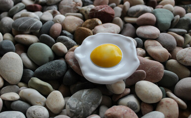 Plastic Single Fried Egg On A Small River Rocks Surface Angle View. Concept Photo About Cooking In The Wild
