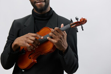 Soulful African American man in elegant black suit playing the violin with passion on white background
