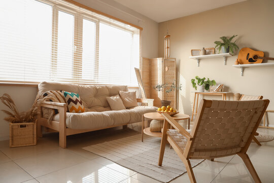 Interior of light living room with wind chime, sofa and armchairs