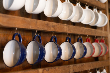 selective focus, many ceramic coffee mugs Hanging on a wooden wall In a country cafe